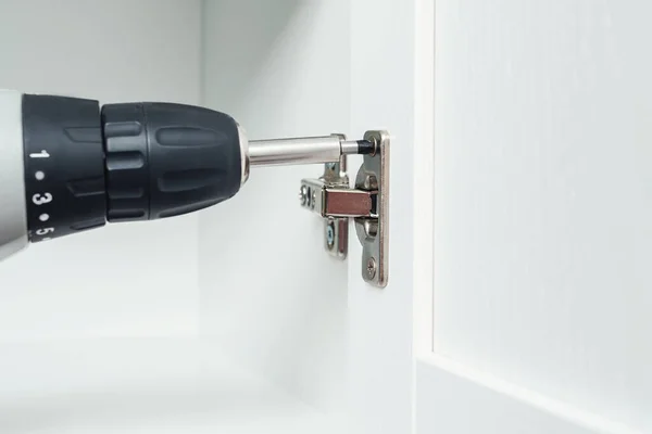 Schroef aandraaien met een elektrische schroevendraaier. Installatie van meubelscharnieren voor deuren — Stockfoto