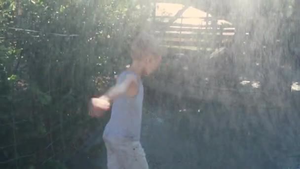 Чарівний дитина крутить і розважається під дощем від зрошувальної системи — стокове відео