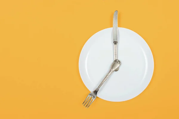 Tempo para jantar, prato como um relógio mostra sete oclock à noite em um fundo amarelo — Fotografia de Stock