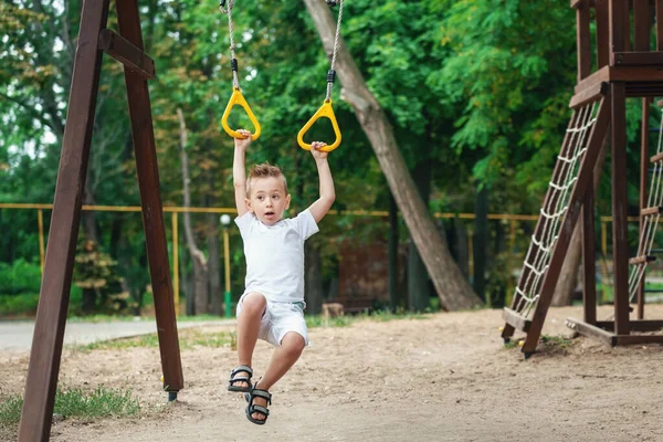 Портрет милого белого мальчика. Ребенок тренируется с кольцами гимнастики — стоковое фото