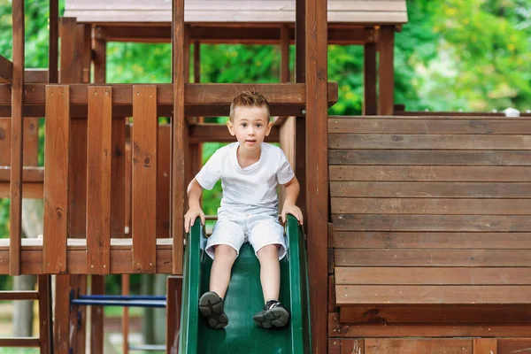 Мальчик играет на детской площадке на открытом воздухе летом. — стоковое фото