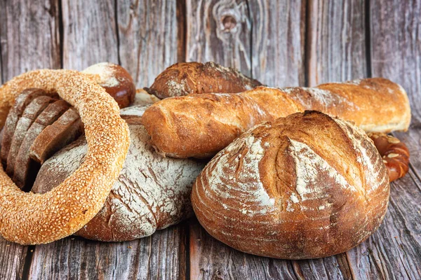 Close-up of assortment of baked bread on wooden table background — Stock Photo, Image