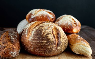 Ahşap masa arkasında çeşitli fırınlanmış ekmekler