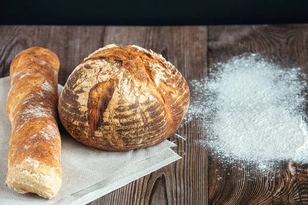 Pão de trigo e baguete e farinha de trigo na mesa de madeira — Fotografia de Stock