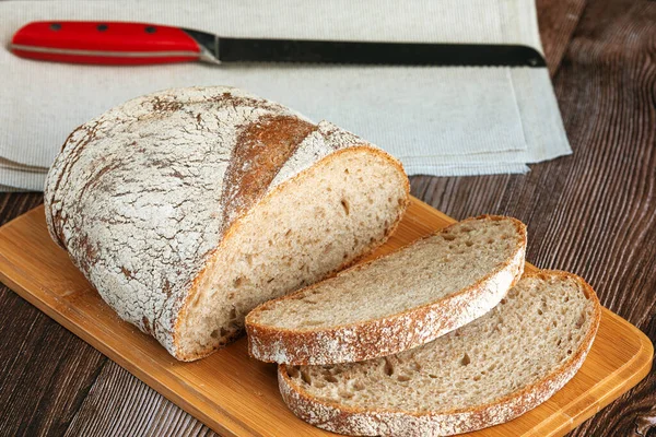 Pan de centeno rebanado con un cuchillo en una tabla de cortar —  Fotos de Stock