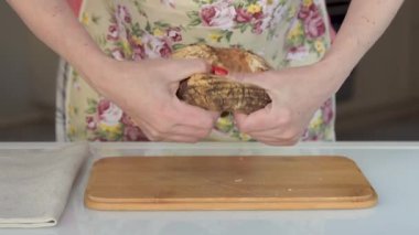 Kadınların elleri bir somun ekmeği ikiye böler.