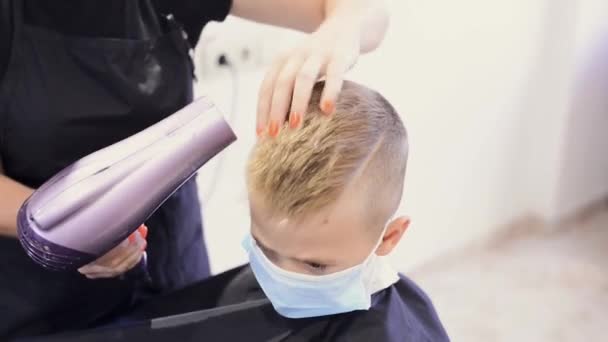 Fryzjer stylizuje włosy swojego klienta za pomocą suszarki do włosów. Fryzjerstwo podczas pandemii COVID-19 — Wideo stockowe