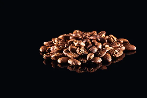 Palone ziarna kawy izolowane na czarnym, błyszczącym tle — Zdjęcie stockowe