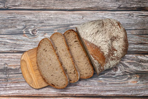 Pan de centeno casero en rodajas en una tabla de cortar —  Fotos de Stock