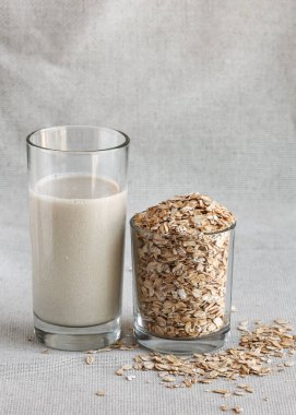 Sağlıklı yulaf sütü uzun boylu, tohumlu bardak içiyor. Dikey fotoğraf