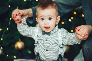 Noel ağacının güzel ışıkları karşısında papyon ve gömlek takan süpriz bebek. Tatil sezonu. Yeni yıl tatili.