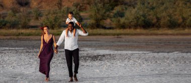 Mutlu melez aile güzel güneşli bir günde sahilde yürüyor.