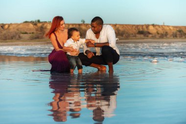 Karışık ırk ailelerini, gün batımında küçük bebekleriyle anne babalarını seviyorlar. Açık havada mutlu bir aile kavramı.