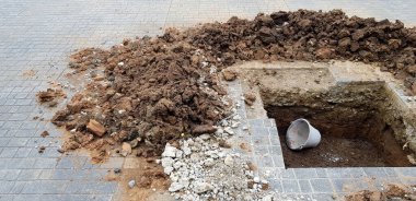 İnşaat alanında fotokopi alanı olan çimento zemindeki çukur, toprak ya da tepecikli çukur. Tehlike bölgesini belirten katı bir sembol ya da işaret yok.