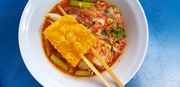 在蓝桌或背景下 用筷子 油炸猪肉汤包在白碗中 把调味平底锅中的海鲜面汤封闭起来 亚洲食物概念 — 图库照片