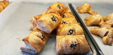 Beyaz kağıda beyaz soslu tavuk turtası ekmekçi dükkanında satılıyor.