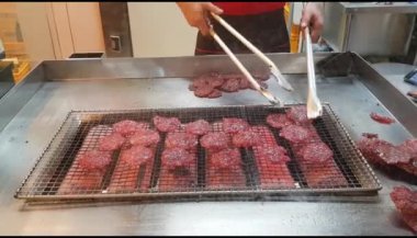Şef ızgarada domuz kıyması pişiriyor. Turistler için ünlü yiyecekler Singapur 'da hatıra olarak alınır. Camdan kaydedilen video