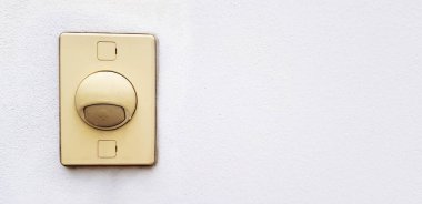 Beyaz beton duvarda izole edilmiş eski sarı plastik kapı zili. Eve ya da binaya doğru kopya alanı ile girmek isteyen insanlar için düğmeye basıp alarm veriyor. Elektronik aygıt