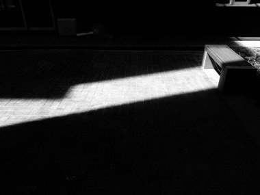 Güneş ışığının gölgesi ve siyah beyaz tonda gölgesi olan ahşap bir bank. Nesne ve Tek Renkli Fotoğraf Sanatı