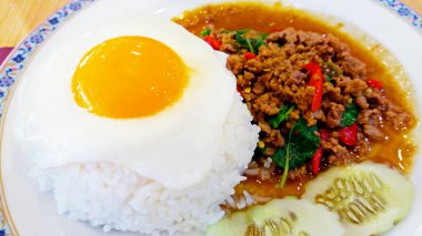 Thai spicy food. Basil fried rice with minced meat and fried egg on top. Fried egg focused. Famous Asian food in Thailand.