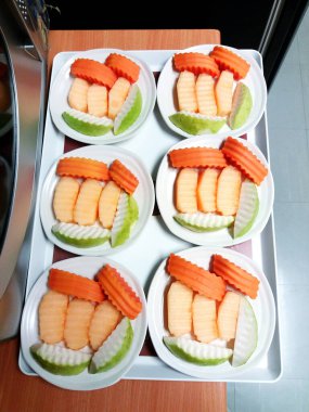 Beyaz tabaklarda bir sürü meyve dilimi var. Papaya, Cantaloupe ve Guava konuklar ve ziyaretçiler için hazırlandı.