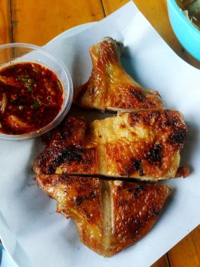 Grilled chicken with spicy sauce on white paper for lunch. Asian food on table.