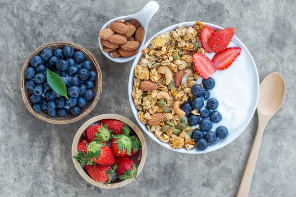 Bowl of homemade granola yogurt with fresh berries, blueberry strawberry almond for topping, top view