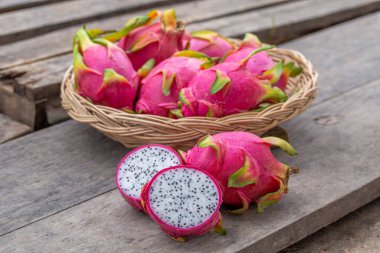 Eski ahşap arka planda ve sepette taze pitaya ya da ejderha meyvesi var..