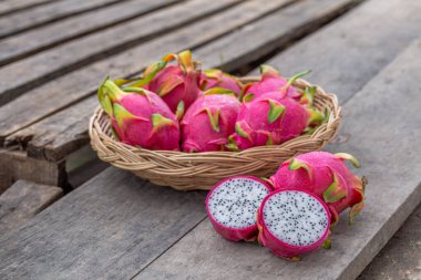 Eski ahşap arka planda ve sepette taze pitaya ya da ejderha meyvesi var..