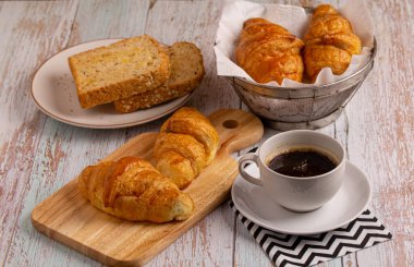 Kahvaltıda taze kruvasan ve tahtadan yapılmış sade kahve ile tam buğday ekmeği.