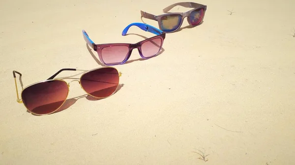 Trzy Okulary Przeciwsłoneczne Umieszczone Suchym Piasku Plaży Narodowy Dzień Okularów — Zdjęcie stockowe