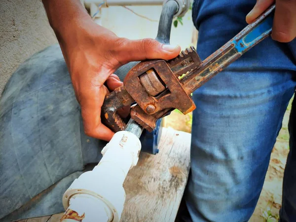 Plumber repairing water fitting with adjustable wrench
