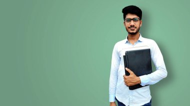 Elinde laptop ve belgelerle gülümseyen genç bir üniversite öğrencisi.