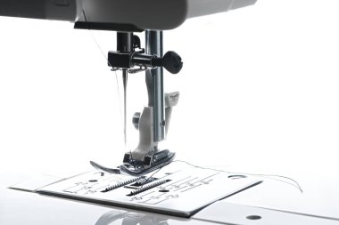 Dikiş makinesinin çalışma alanının orta yatay görüntüsü. Tabaka ayak iğnesi ipliği ve yukarıdaki yuvaların hepsi görünür..