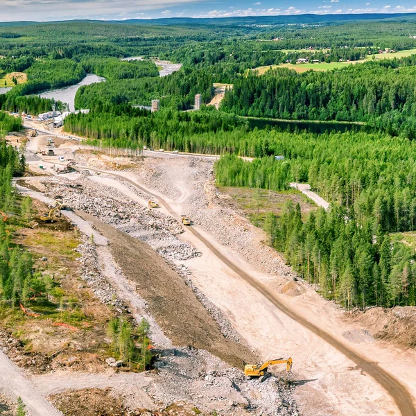 Umea nehri üzerinde yeni otoyol ve köprü inşaatı üzerine insansız hava aracı fotoğrafı - birçok ağır endüstriyel makine birlikte çalışır - çöp kamyonları, buldozer ve kazıcı. İnşaat alanında yüksek irtifa genel görünümü
