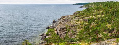 Kayalık sahil şeridinin nefes kesici panoramik manzarası ve yemyeşil orman İsveç 'te denizin engin genişliğiyle buluşuyor, sakin ve resimsel bir manzara yaratıyor.