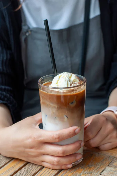 Bir bardak soğuk latte ve bir kadının ellerinde dondurma.