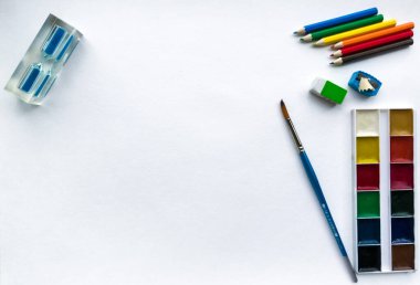  Okul ve yaratıcılık, çizim ve el işleri için kırtasiye malzemesi (suluboya boyalar, renkli kalemler, defter, kum saati) sağda ve solda metinler için yeri olan beyaz suluboya kağıdına karşıdır.