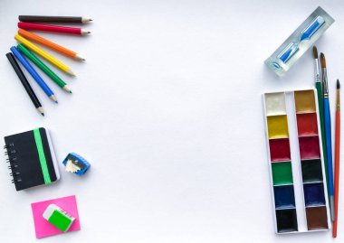  Okul ve yaratıcılık, çizim ve el işleri için kırtasiye malzemesi (suluboya boyalar, renkli kalemler, defter, kum saati) sağda ve solda metinler için yeri olan beyaz suluboya kağıdına karşıdır.