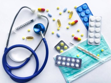 Tıbbi malzemeler doktor, hastanın tedavisi için ödenek - steteskop, koruyucu maske, haplar, arka planda beyaz dokulu kaba saba bir çarşafın şırınga