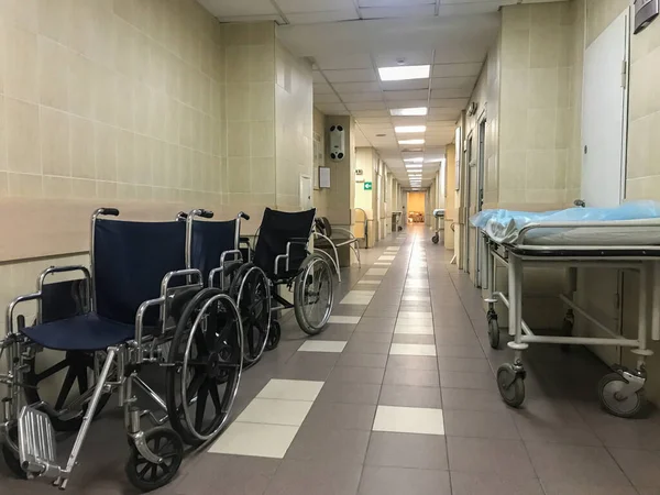 Hospital wheel chairs and stretcher trolley in empty hospital hallway