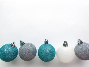 mavi (turkuaz) parlak Noel topları, beyaz, gümüş renkli, beyaz arka planda uzanıp yazı için boşluk bırakırlar. Noel ve tatil arifesi kavramı