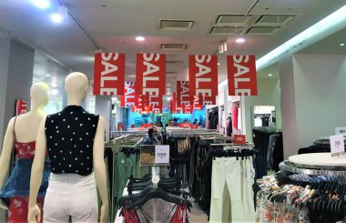 Moskova, Rusya, Temmuz 2019: İki kel kadın manken bir giyim mağazasında ürünlerin arasında duruyor ve alıcılara ve satışın kırmızı pankartlarına bakıyor