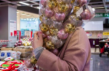 Moskova, Rusya, Eylül 2019: Pembe montlu bir kız Noel hediyeleriyle dolu bir mağazada Noel balosu paketleri tutuyor. Noel, satış, hediyeler için hazırlık kavramı