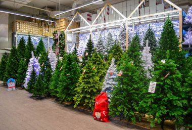 Moskova, Rusya, Kasım 2019: Bir sürü yapay ağaç, yeşil, beyaz, çelenkli, mağazada satılıyor. Yakında bir çanta dolusu hediye var.