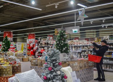 Moskova, Rusya, Kasım 2019: Noel alışverişi. Büyük bir mağazada Noel süslemeleri, heykelcikler, yeni yıl için dekor, alışveriş arabası olan bir adam mallara bakıyor.
