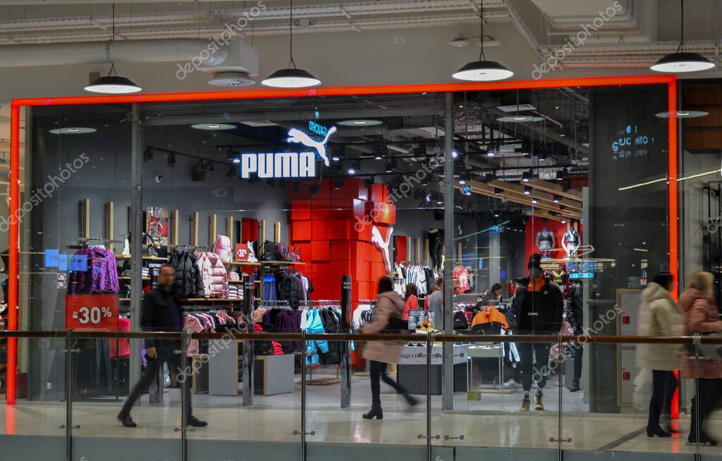Moscow, Russia, November 2019: Brand store sportswear and footwear Puma. Entrance in the shopping mall, windows, storefronts, buyers look at the goods inside and blurred people go by outside