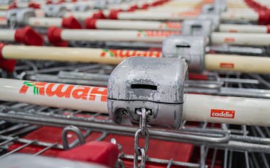 Moskova, Rusya, Haziran 2020: Kilitli Auchan alışveriş arabalarının kulplarında bozuk para işleten alıcıya yakın çekim