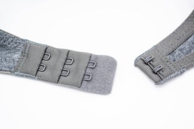 Beyaz arka planda kancaları olan gri pamuklu sütyenin yakın çekimi