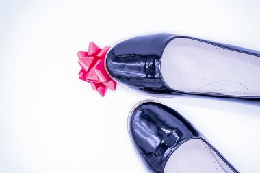 Kadınların siyah deri ayakkabıları, çiçek şeklinde kırmızı ipek bir fiyonka basılmıştı..